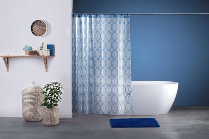 Bei diesem Bild handelt es sich um ein Milieu-Foto in einem Badezimmer. Hierbei sieht man einen aufgehängten Duschvorhang mit blauem Ring-Muster, dahinter eine Badewanne. Vor dem Vorhang auf dem Boden befindet sich eine Badematte in der Farbe dunkelblau.
