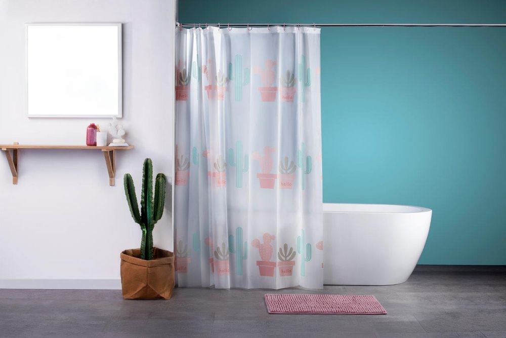 Bei diesem Bild handelt es sich um ein Foto in einem Badezimmer. Hierbei sieht man einen aufgehängten Duschvorhang mit Kaktus-Muster, dahinter eine weiße Badewanne. Vor dem Vorhang auf dem Boden befindet sich ein rutschfester Badvorleger in der Farbe rosa.